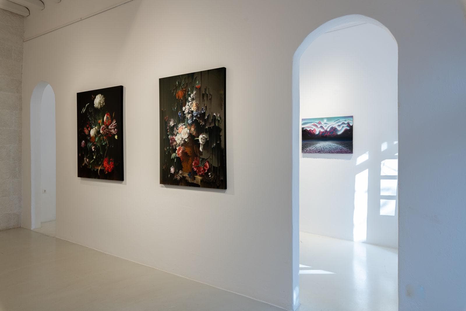 A bright gallery room with arched doorways and paintings on white walls