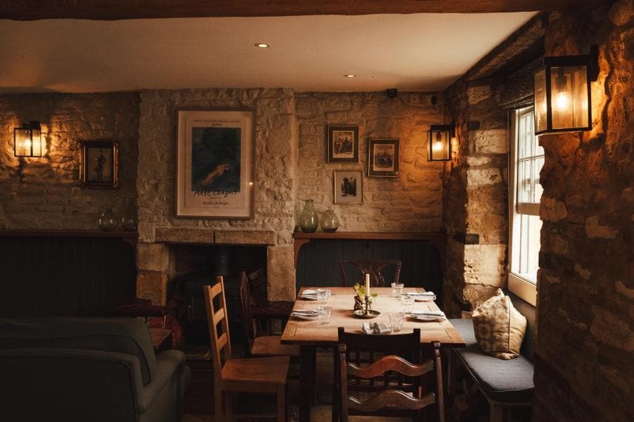 A candlelit dining room with stone walls and a fireplace
