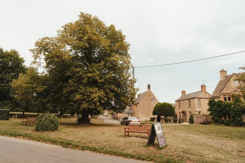 Kingham village green with a mature tree and stone houses
