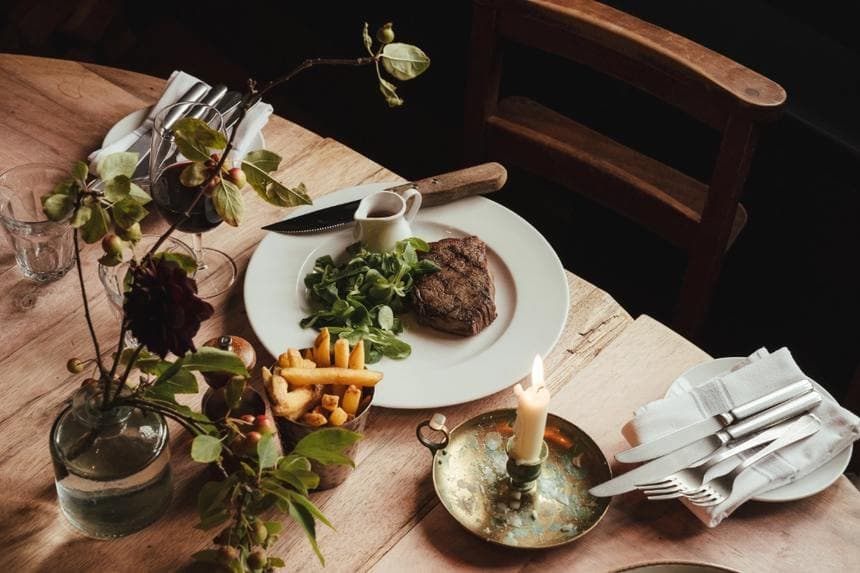 Steak and chips on a wooden table with a candle