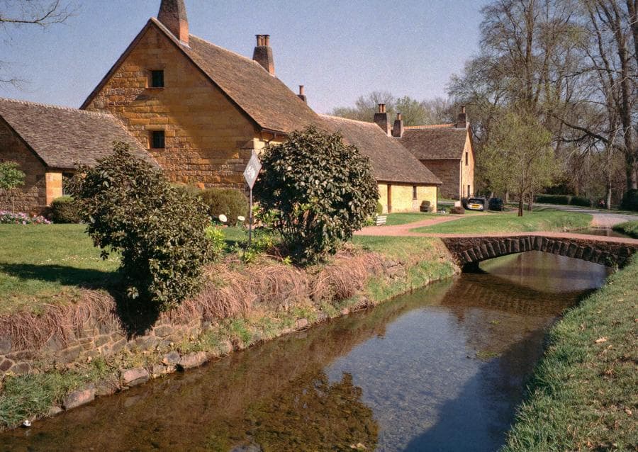 Stone cottages beside a shallow stream with a little bridge