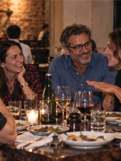 A small group talking over dinner at a candlelit restaurant table