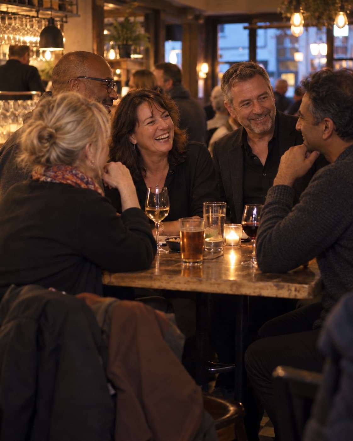 A group laughing around a table of drinks in a bar