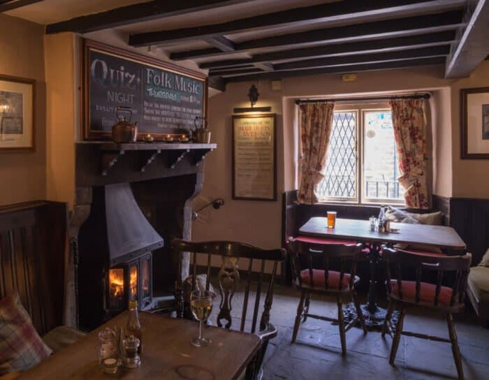 A beamed dining room with a log burner and a leaded window