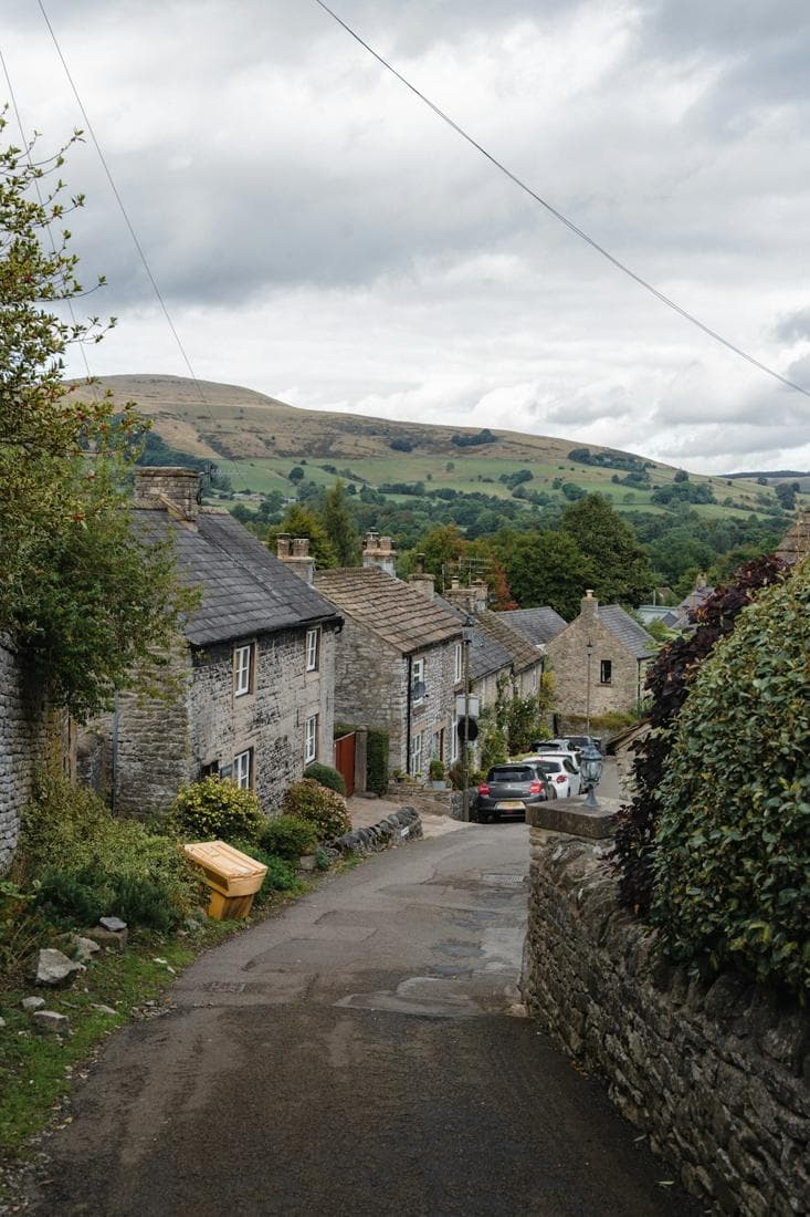 Stone houses along a lane in Castleton, with hills beyond