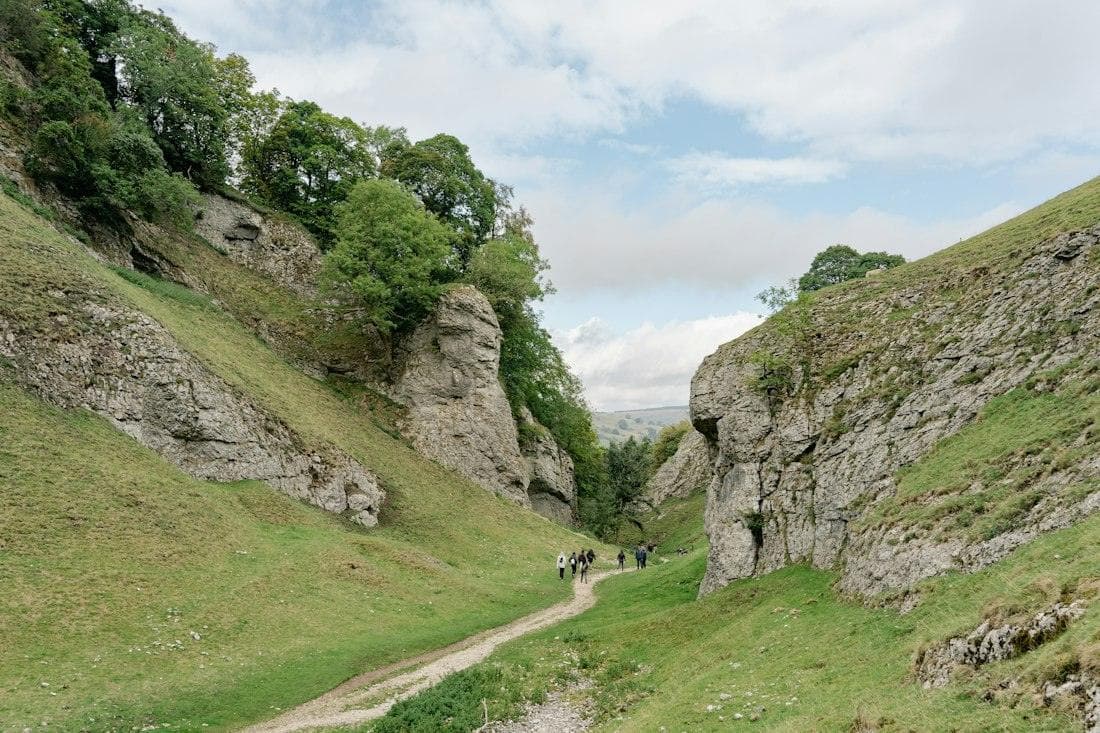 A small group walking together along a grassy path between limestone hills