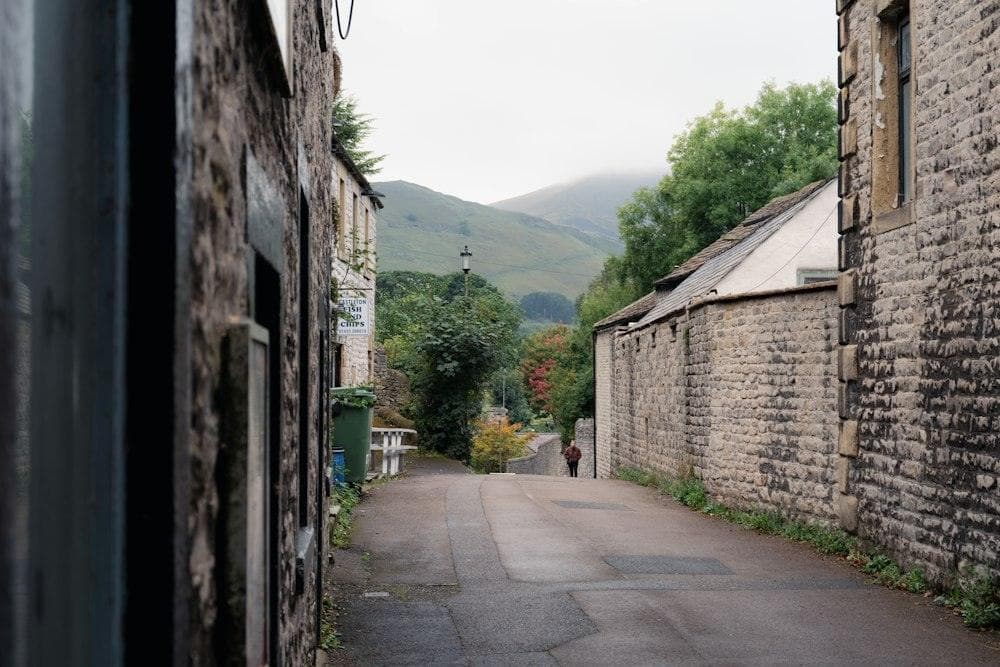 A narrow village lane leading out towards green hills