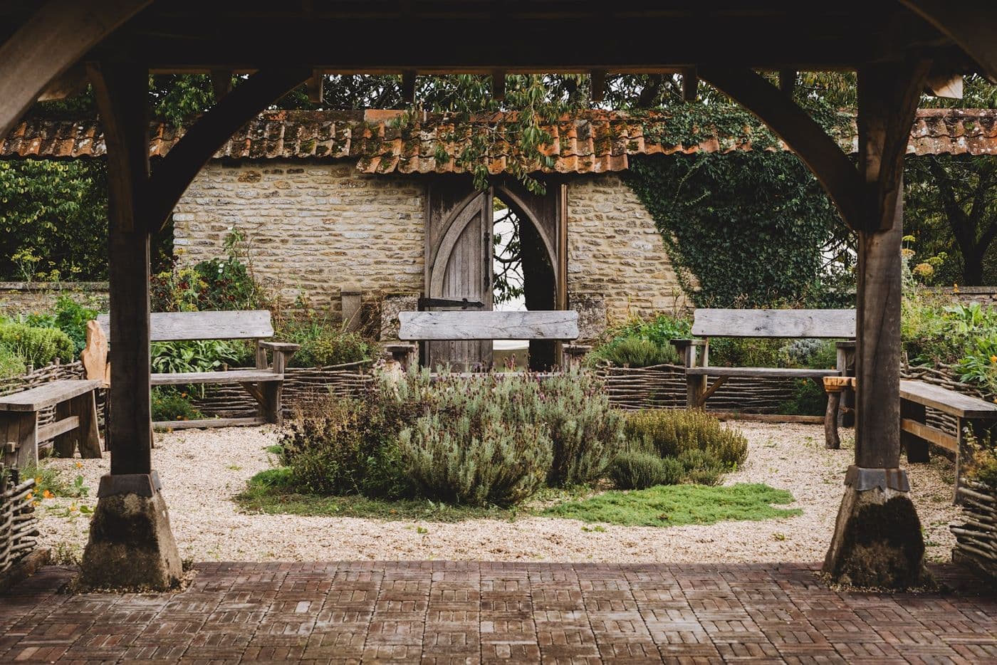 The walled garden: herb beds under the oak pavilion, the gothic door in the wall behind